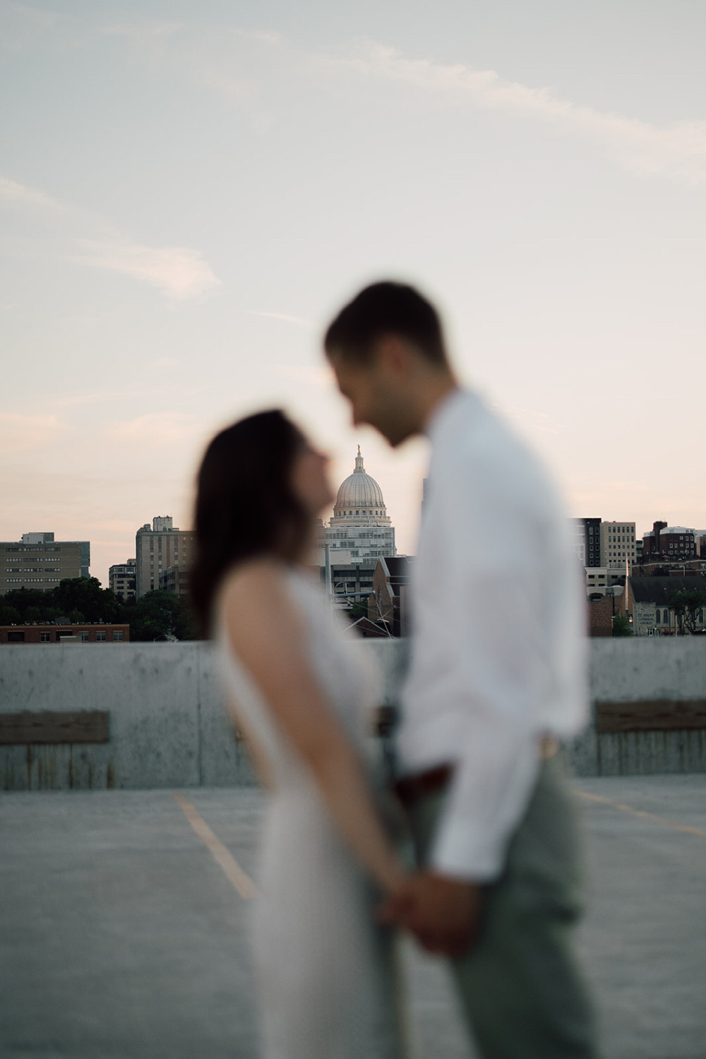 couple stands facing each other and madison capitol is behind them in the distance.