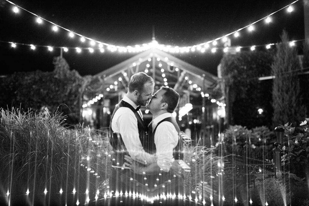 Two grooms embrace at night on top of the Atrium in Milwaukee