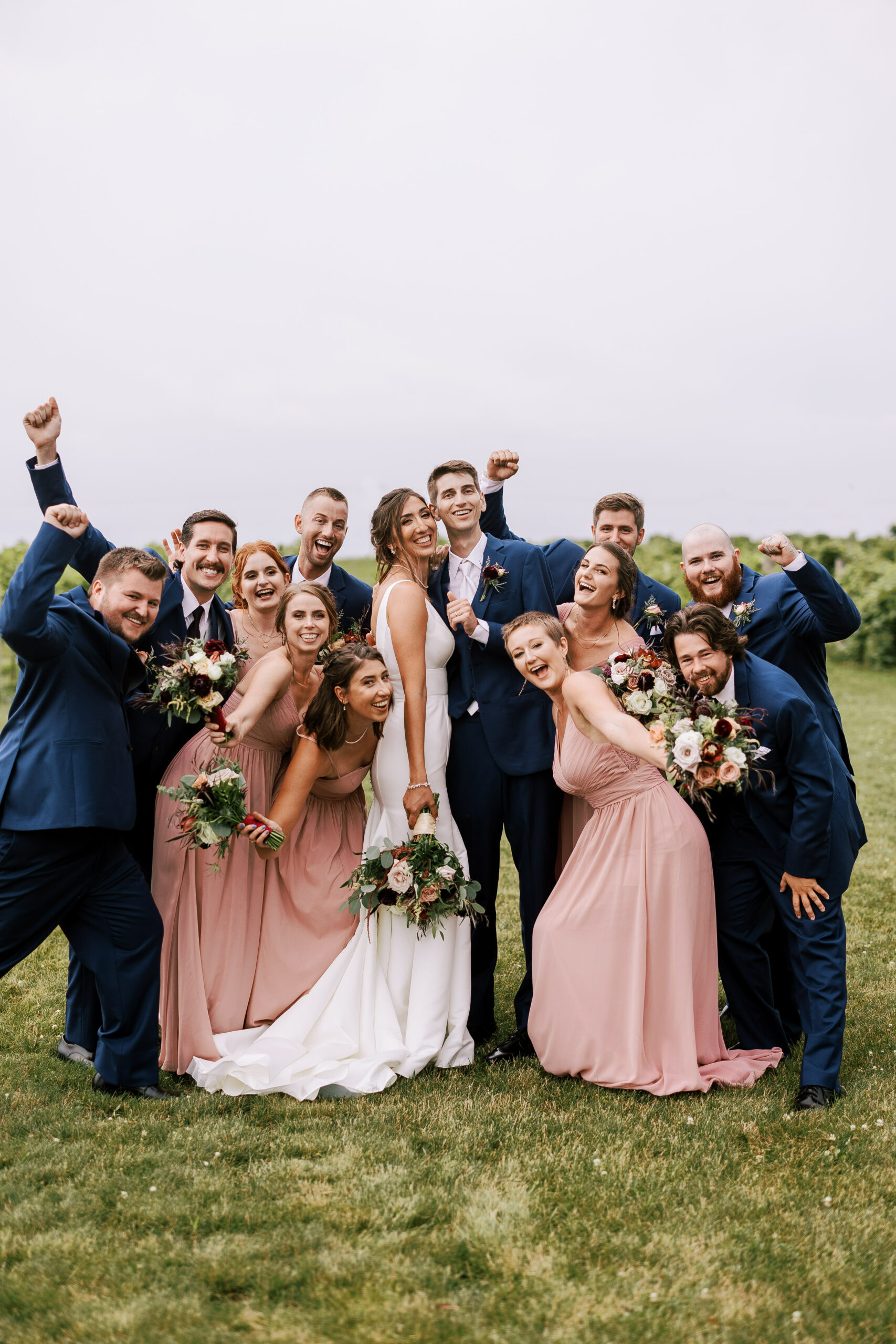 wedding party gathers around bride and groom and cheers towards the camera