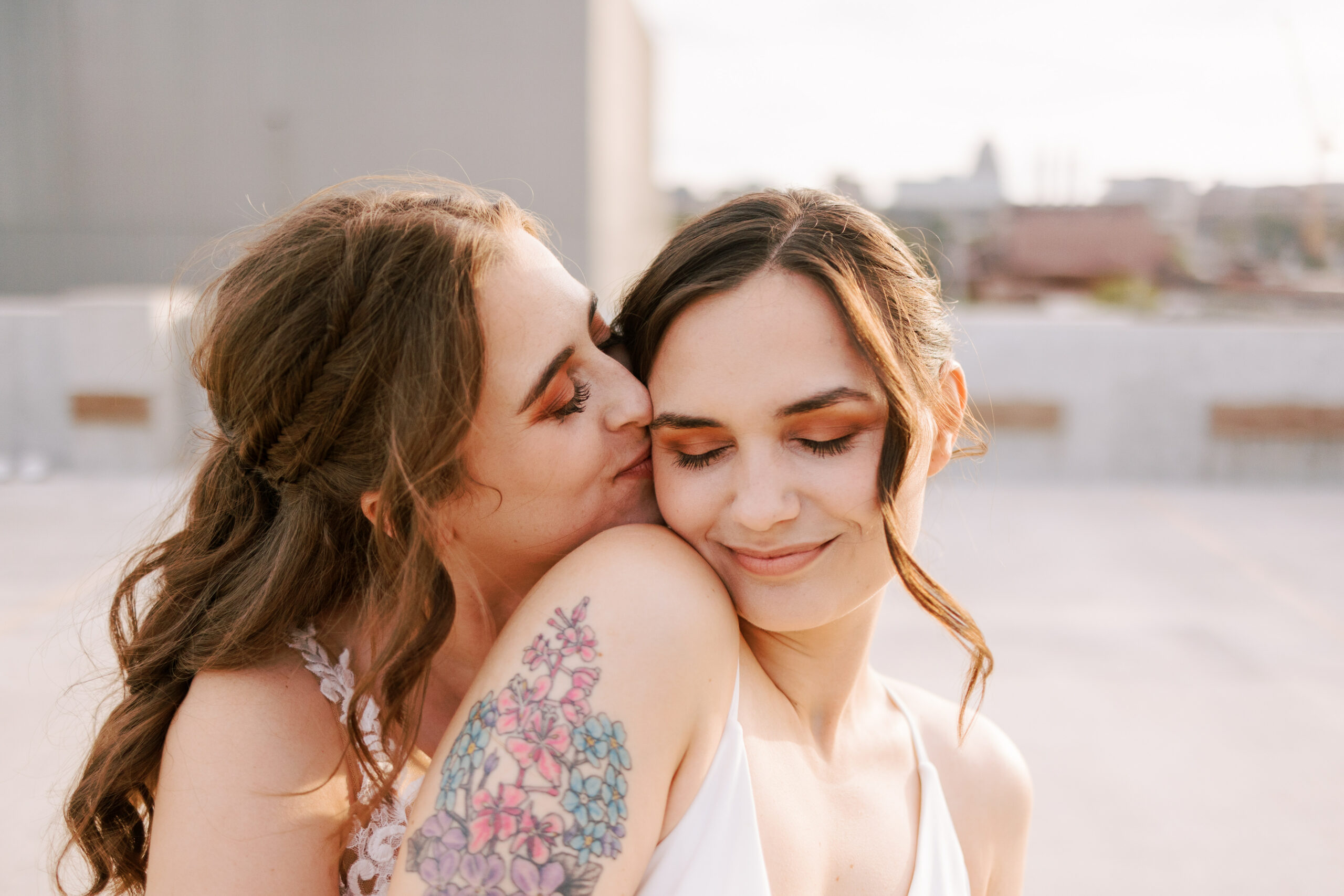 two brides embrace and snuggle on a rooftop in madison wisconsin