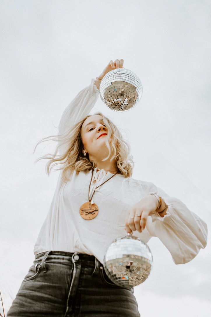 Anya Kubilus holds two disco balls in her hands as her hair blows in the wind
