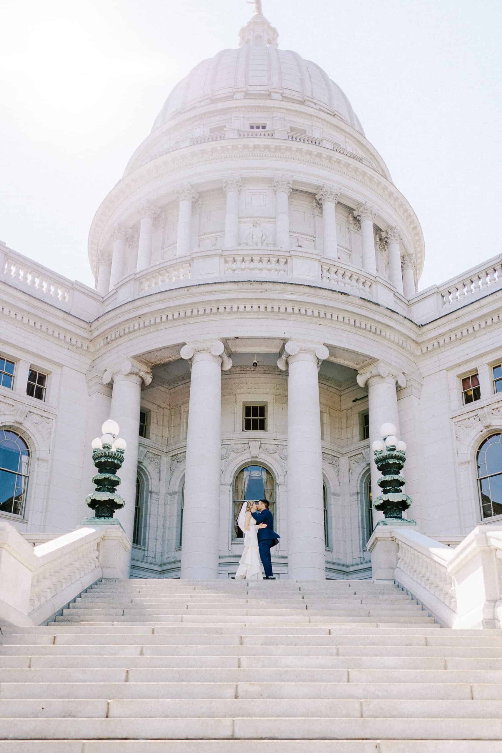 couple kisses at the madison capitol on their wedding day in early fall