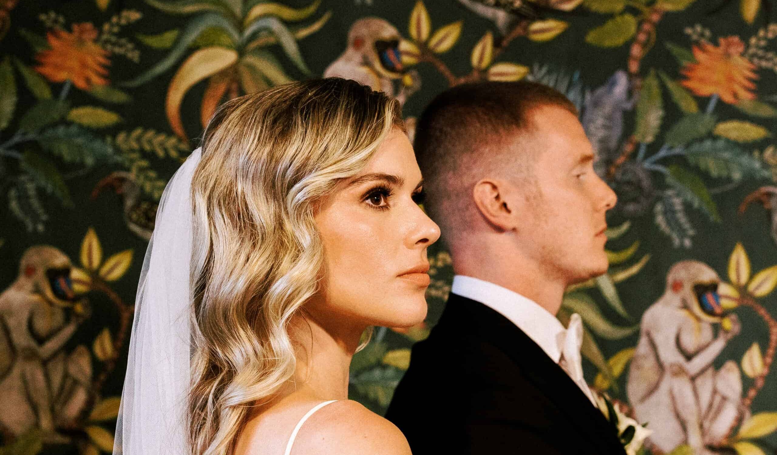 bride and groom stand in front of colorful and tropical wall at the howard in oshkosh, wisconsin