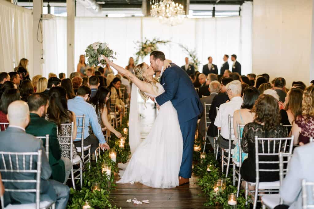 bride and groom kiss as they walk down the aisle at their industrial modern wedding at loft28west