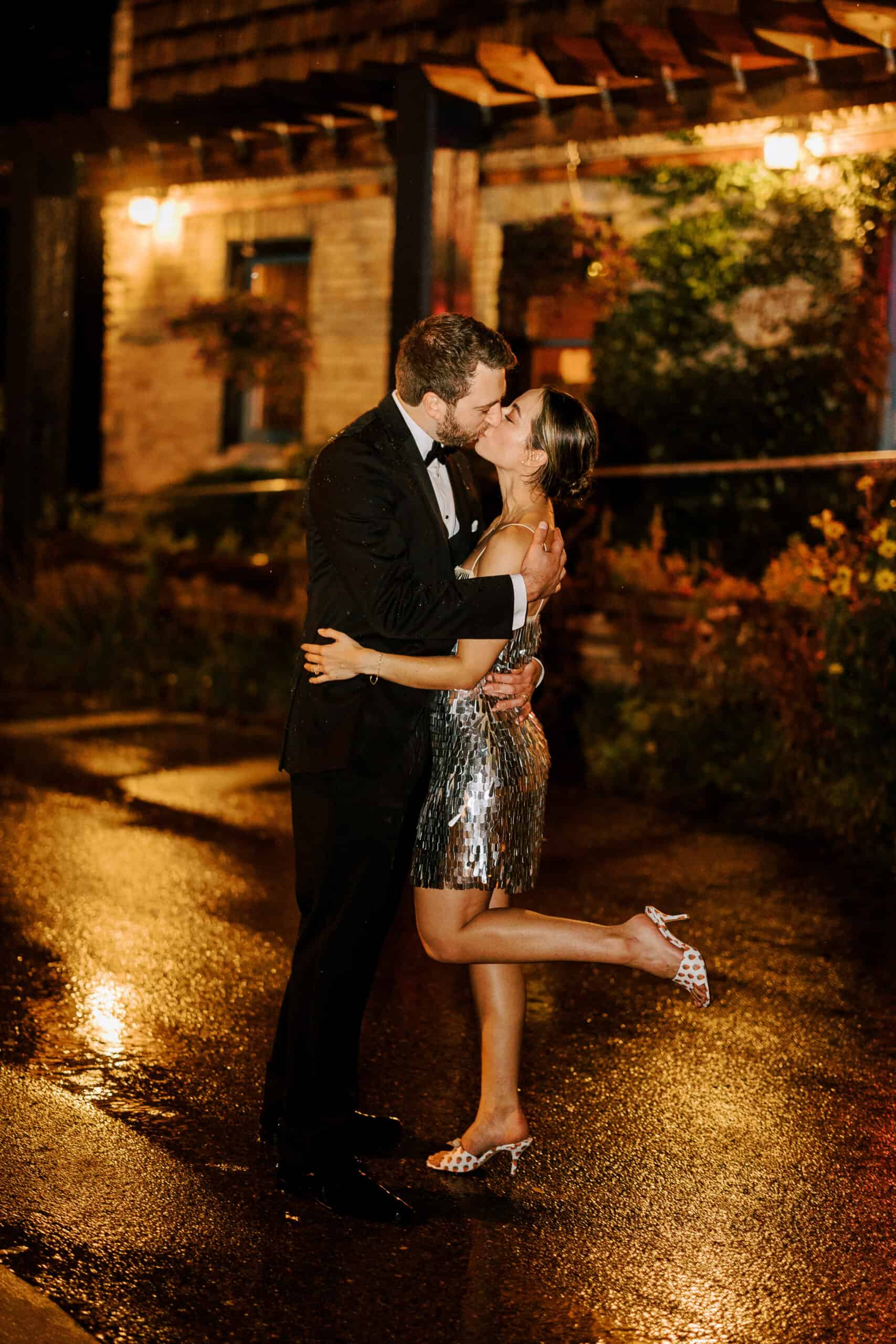 couple kisses outside their wedding venue in madison on a rainy night
