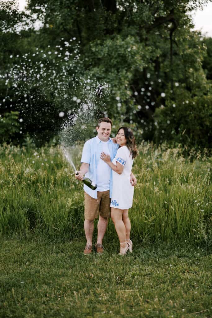 couple pops champagne during their engagement session in madison wisconsin