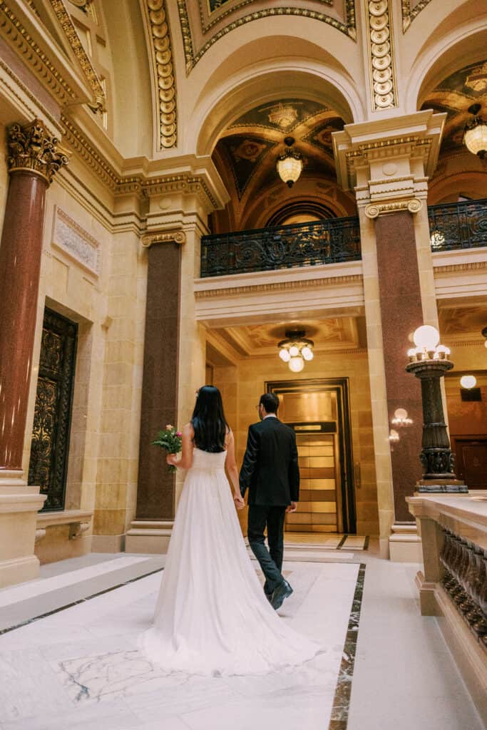 bride and groom walk side by side in madison's capitol building during their elopement.