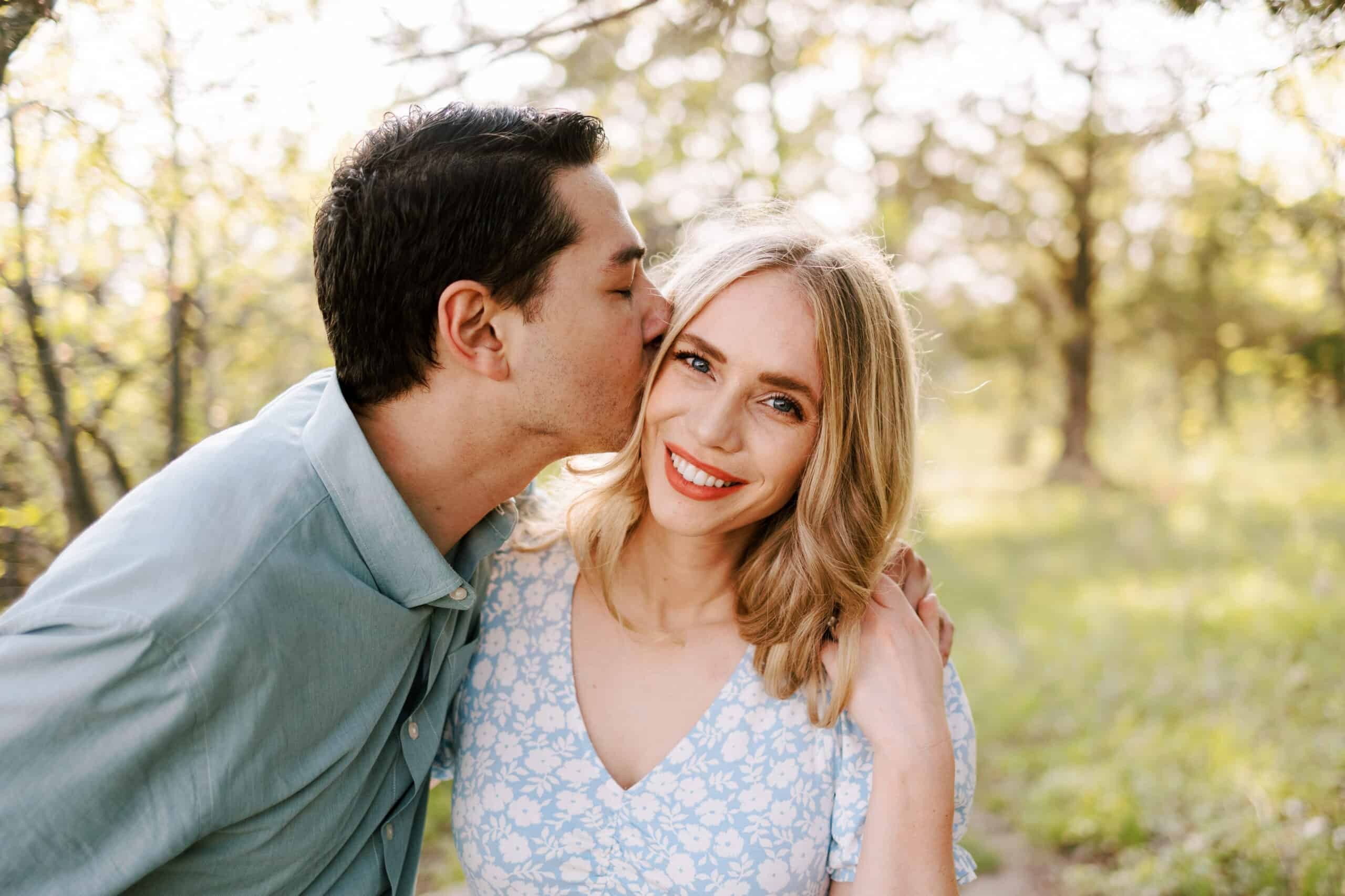 guy kisses girl on cheek during their spring engagement session at devil's lake