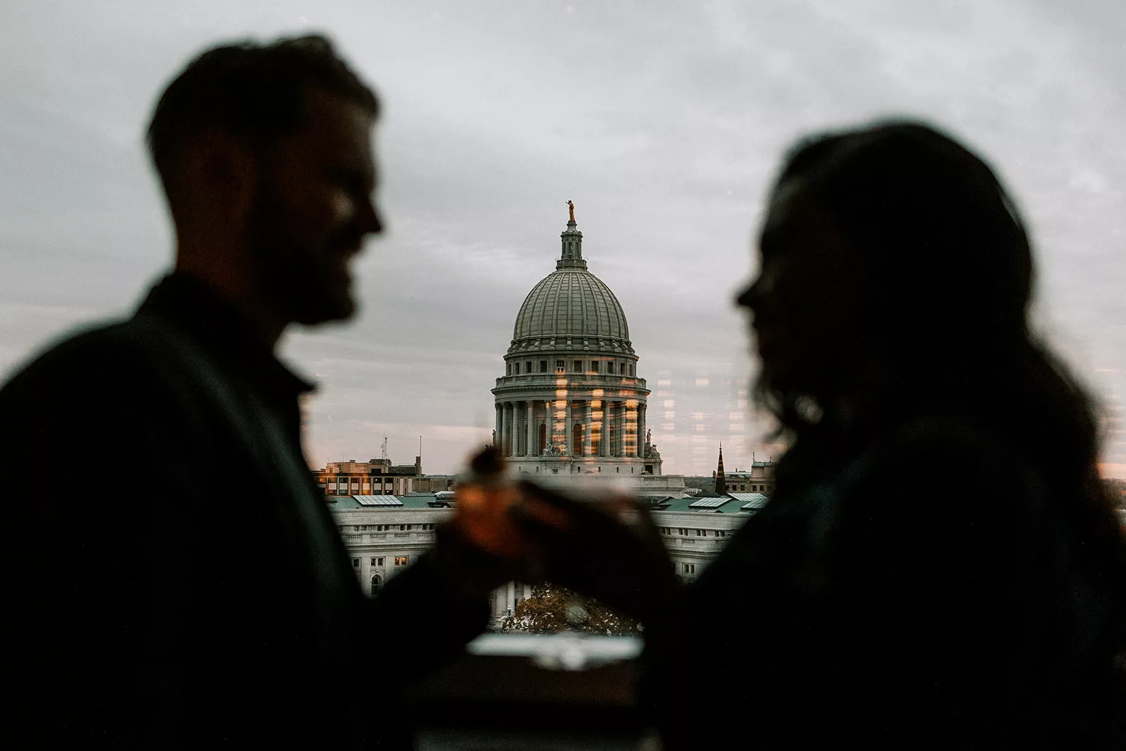 couple enjoys a drink at eno vino in downtown madison with the capitol building behind them