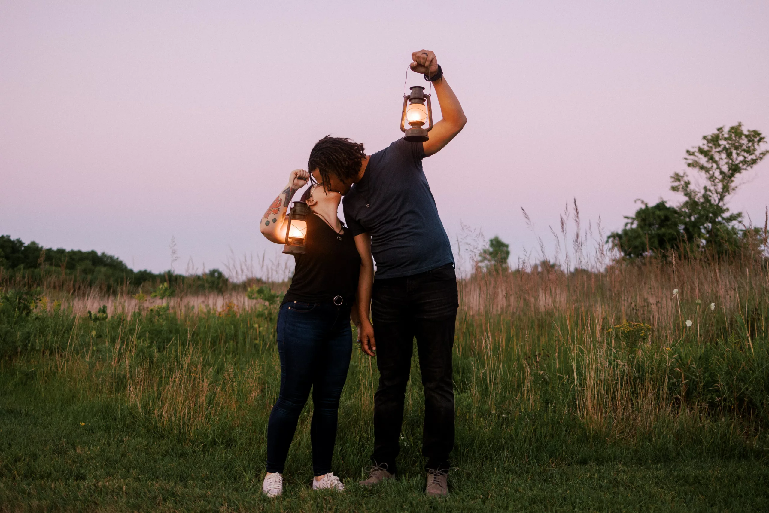 couple holds up lanterns and looks at each other during their engagement session at retzer nature center in waukesha wi