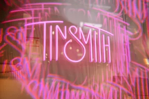 neon light sign with the Tinsmith's logo and a creative effect.