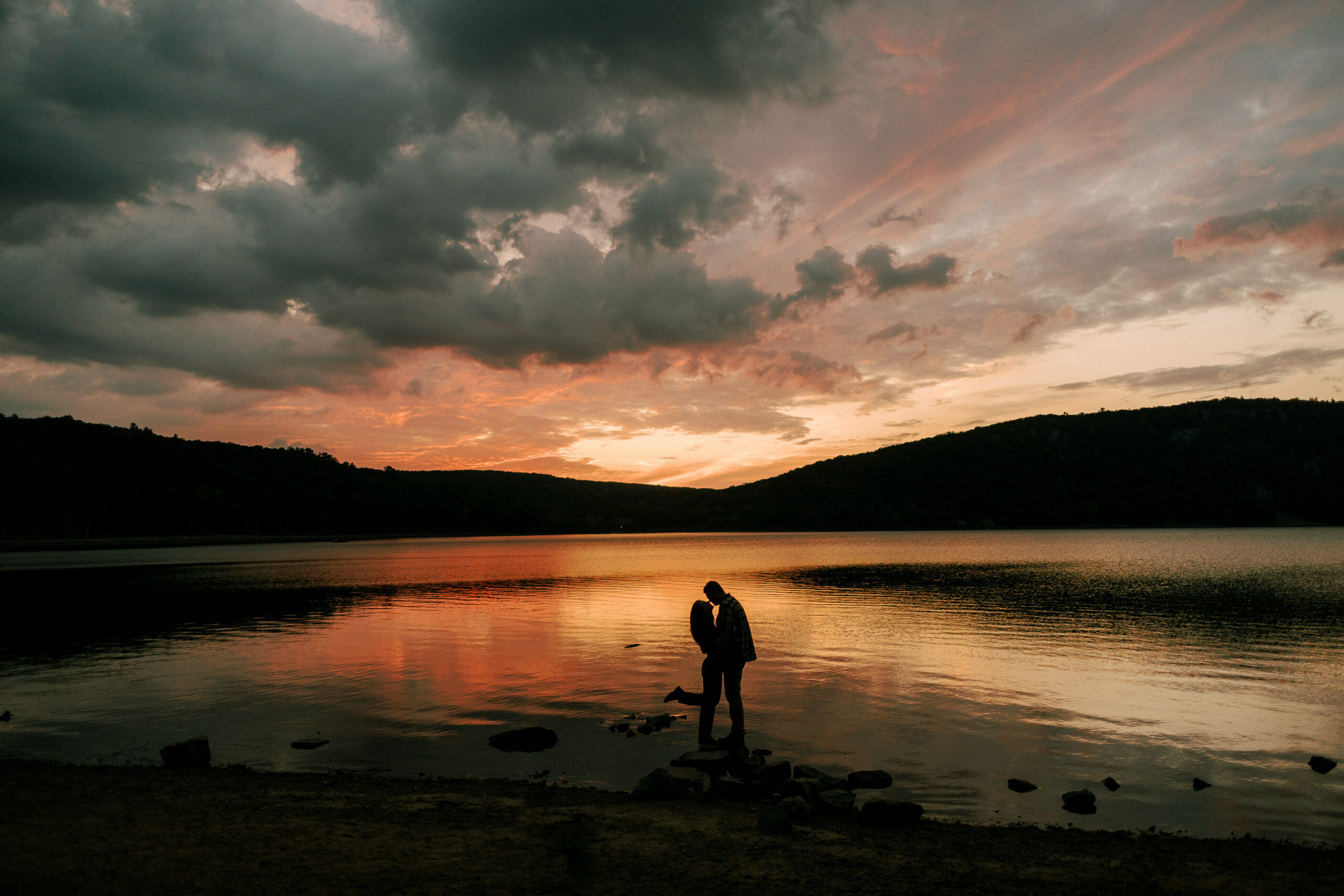 Couple kisses as sun sets behind hills at Devil's Lake in Wisconsin