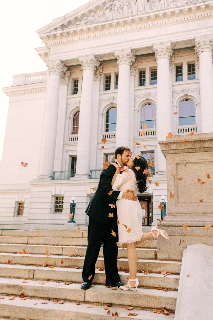 couple kisses at the top of the capitol steps in madison wisconsin on their elopement day