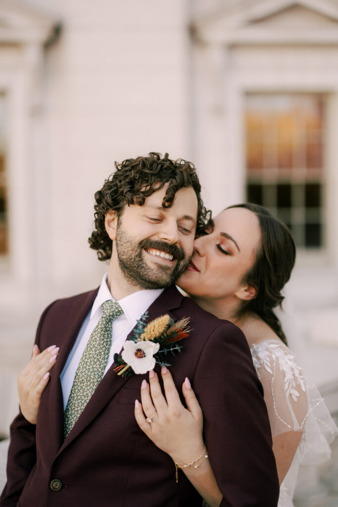 bride and groom embrace at the capitol building of wisconsin on their elopement day