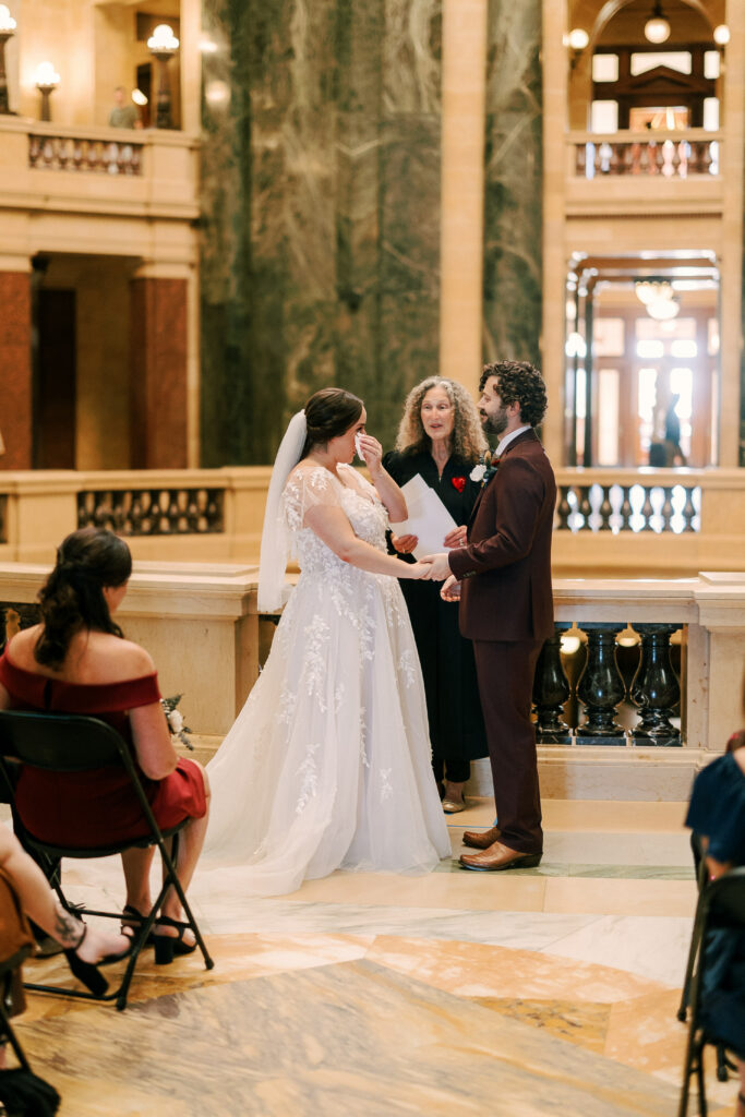 couple shares their vows during their ceremony in the madison wisconsin capitol building with their close family and friends