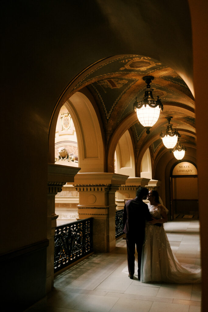 bride and groom embrace in the capitol building of wisconsin on their elopement day