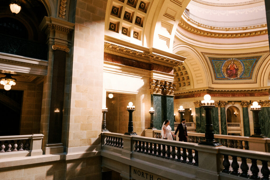 bride and groom walk in the capitol building of wisconsin on their elopement day