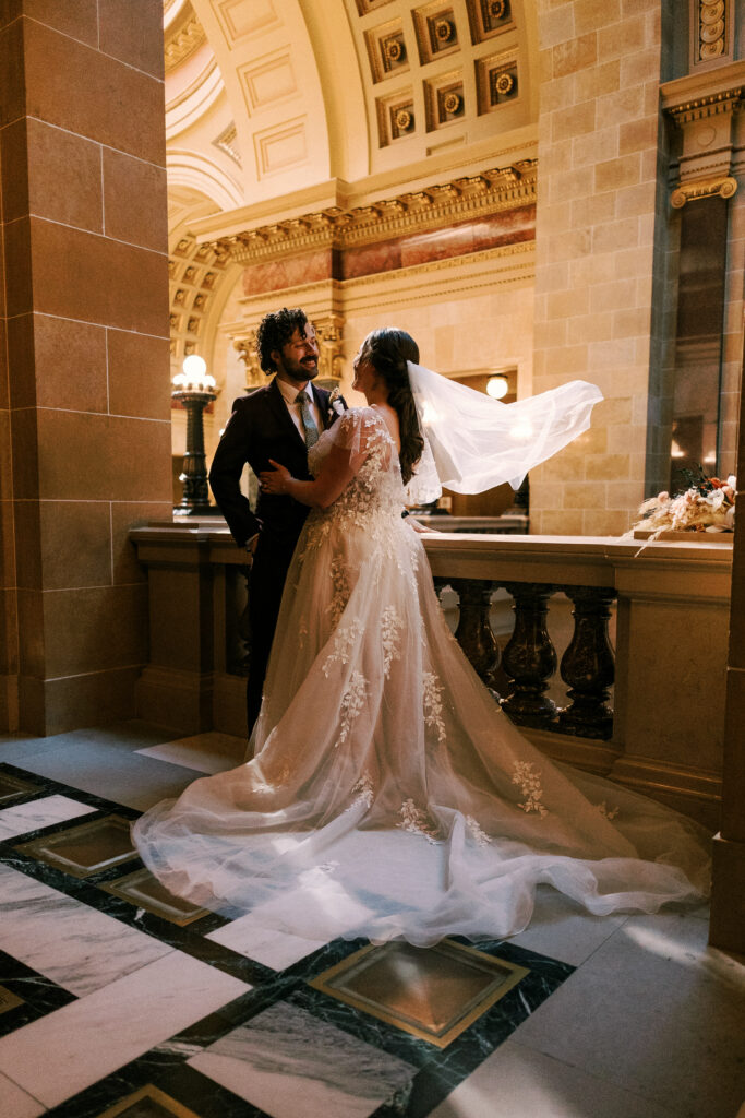 bride and groom embrace in the capitol building of wisconsin on their elopement day