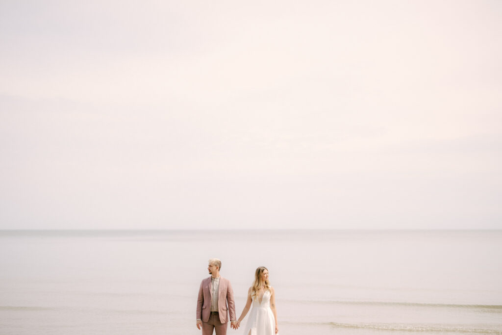 bride and groom stand along the lake's edge during their intimate wedding in milwaukee