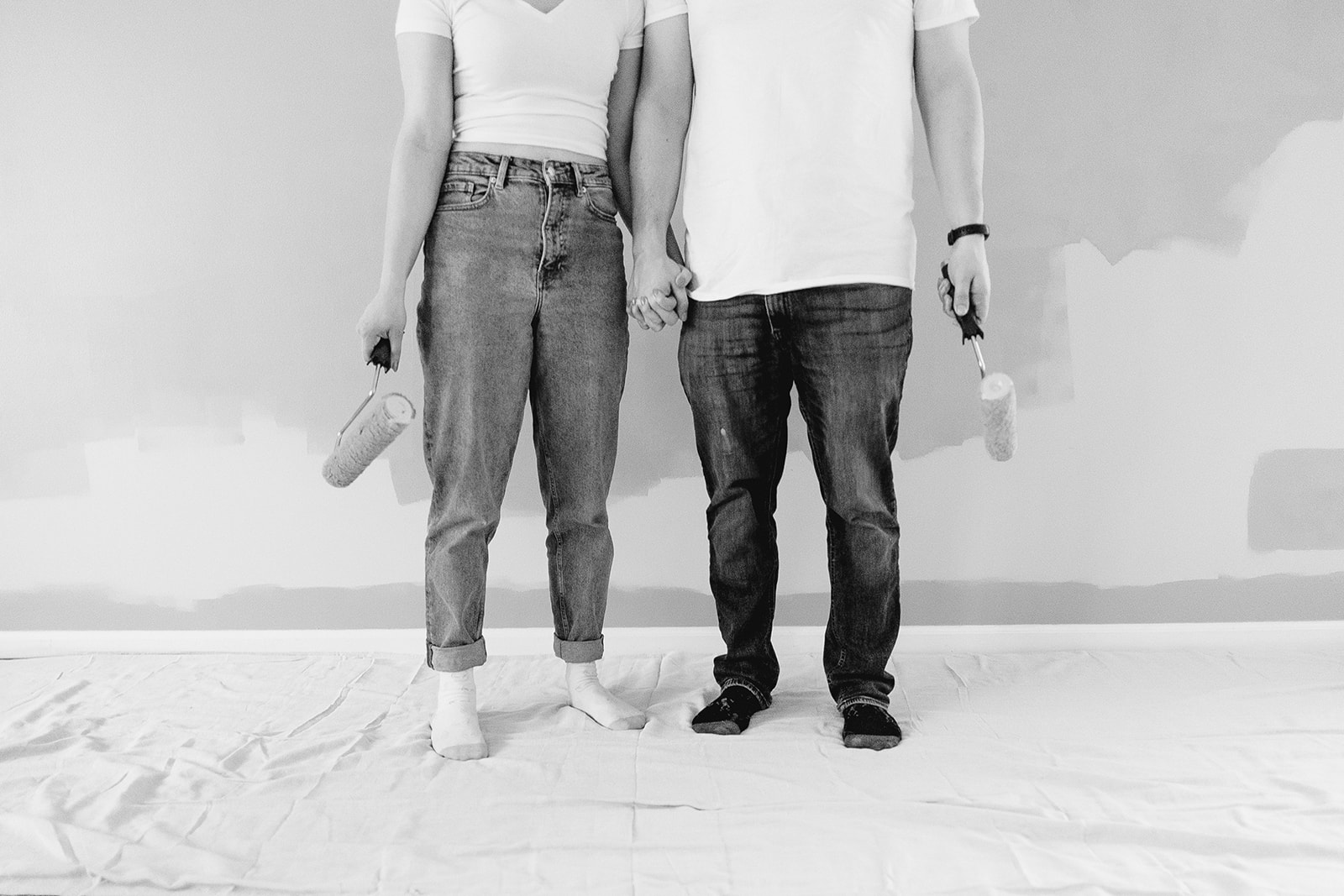 couple holds paint rollers as they paint their new home during their chicago engagement session