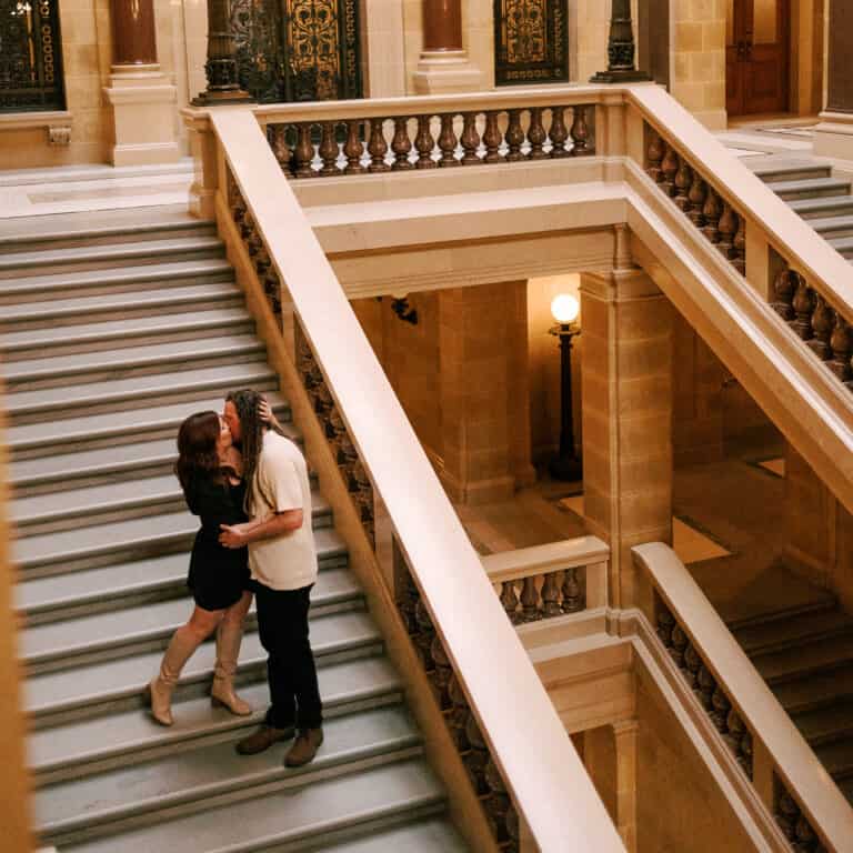 engaged couple kisses on the steps inside the Wisconsin Capitol building in Madison